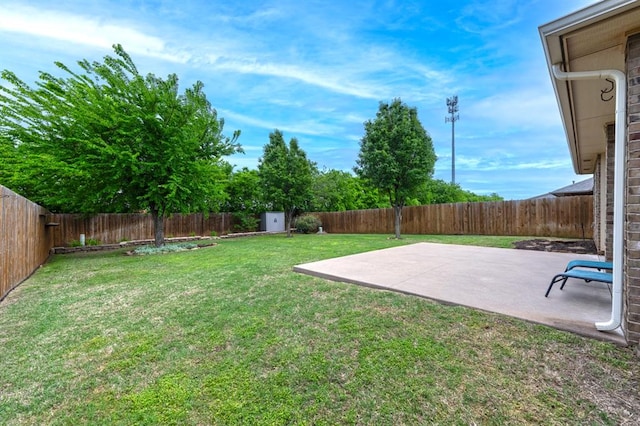 view of yard with a storage shed, a fenced backyard, and a patio area