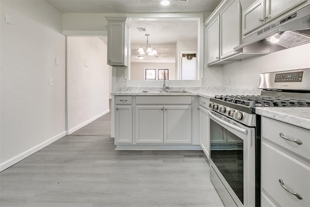 941 SW 48th St, Oklahoma City, OK 73109 - kitchen featuring stainless steel gas range oven, under cabinet range hood, a sink, a chandelier, and light wood-type flooring