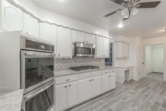 kitchen with appliances with stainless steel finishes, ceiling fan, backsplash, and white cabinetry