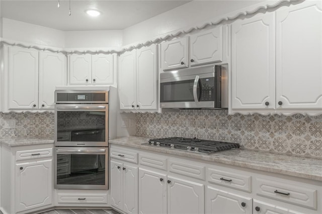 kitchen with white cabinets, appliances with stainless steel finishes, and tasteful backsplash