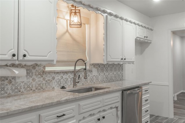 kitchen with a sink, light stone counters, white cabinets, and backsplash