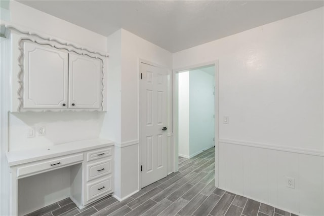 unfurnished office featuring a wainscoted wall and wood tiled floor