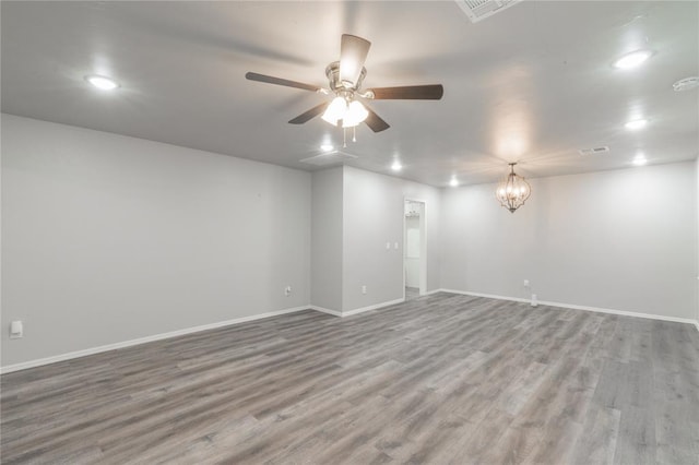 spare room featuring recessed lighting, baseboards, wood finished floors, and ceiling fan with notable chandelier