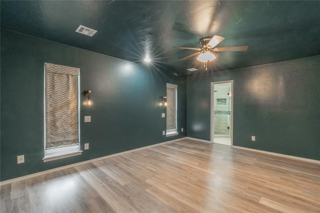 empty room with visible vents, baseboards, ceiling fan, and wood finished floors