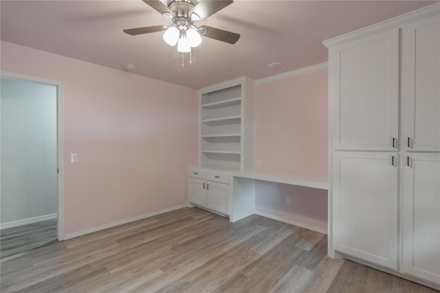 interior space featuring baseboards, a ceiling fan, light wood-style flooring, and built in study area