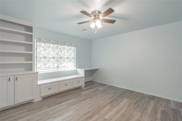 interior space featuring baseboards, ceiling fan, light wood-type flooring, and visible vents