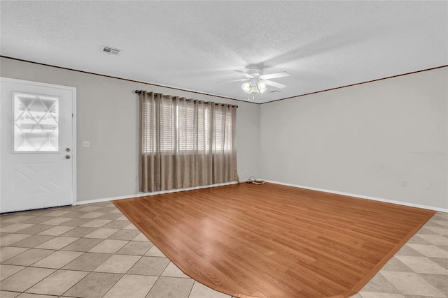 foyer entrance with a textured ceiling, visible vents, a ceiling fan, and light tile patterned floors