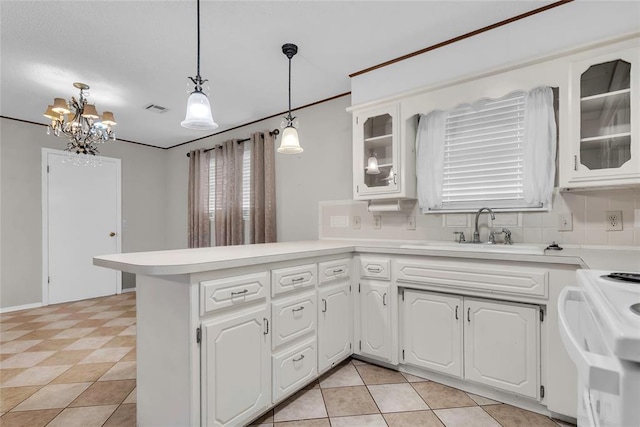 kitchen with range, light countertops, a sink, visible vents, and a peninsula
