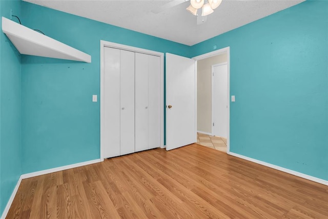 unfurnished bedroom featuring a closet, ceiling fan, wood finished floors, and baseboards
