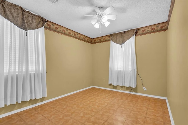 spare room featuring a textured ceiling, ceiling fan, baseboards, and light floors
