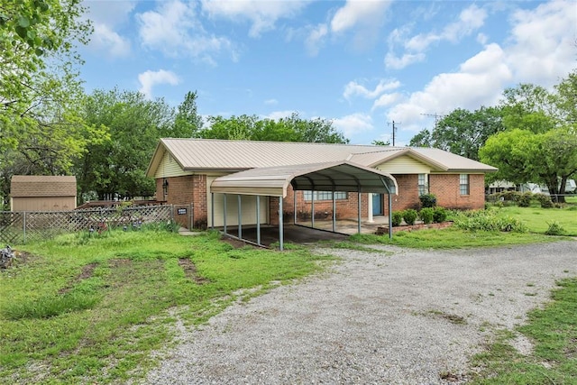 exterior space with a shed, a carport, brick siding, gravel driveway, and fence