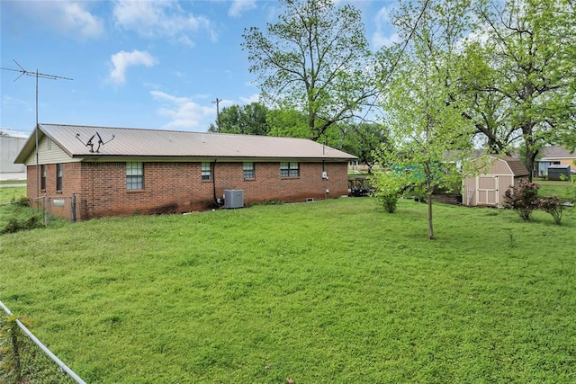 rear view of house featuring an outdoor structure, a yard, brick siding, a storage shed, and central AC