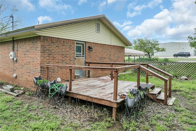 back of house with a deck, brick siding, and fence