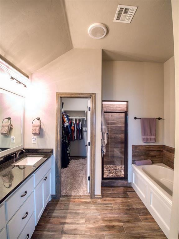 2216 Wheatheart Dr, Yukon, OK 73099 - bathroom featuring a garden tub, wood finished floors, visible vents, vanity, and a spacious closet