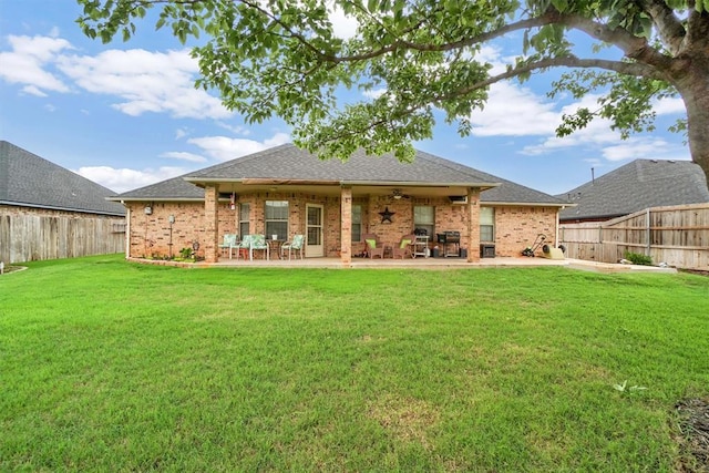 back of house with ceiling fan, a patio, a fenced backyard, brick siding, and a yard