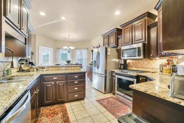 kitchen featuring light stone counters, appliances with stainless steel finishes, backsplash, and a notable chandelier