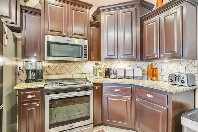 kitchen with a toaster, appliances with stainless steel finishes, backsplash, and light stone counters