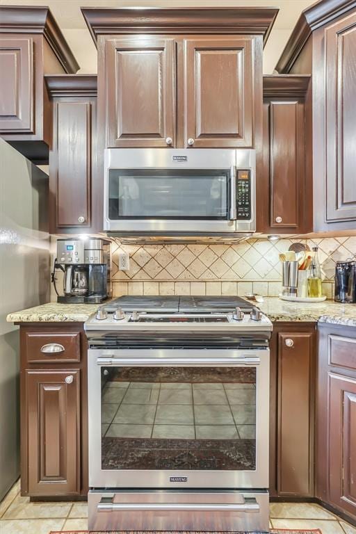 kitchen featuring backsplash, light stone countertops, and appliances with stainless steel finishes