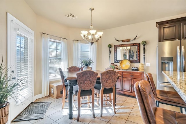 dining room with a notable chandelier, light tile patterned floors, and visible vents