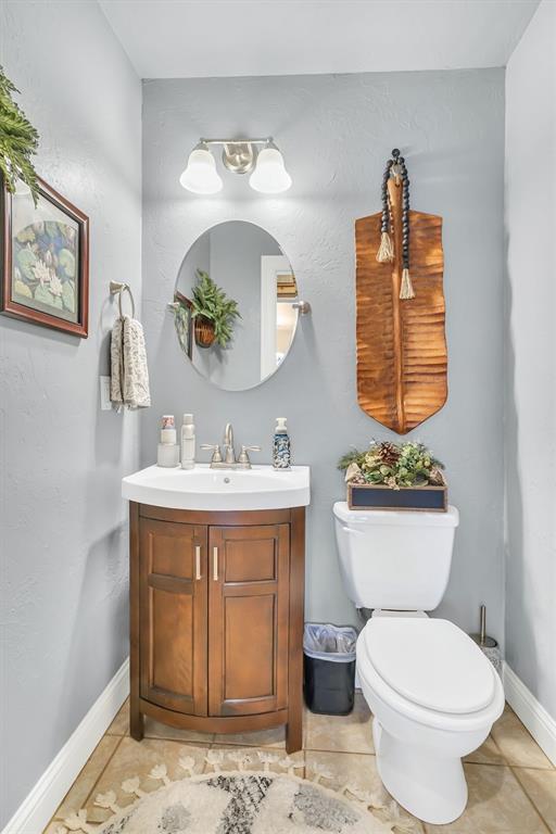 half bathroom with vanity, baseboards, and toilet