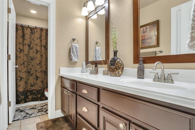 bathroom with double vanity, a sink, tile patterned floors, and toilet