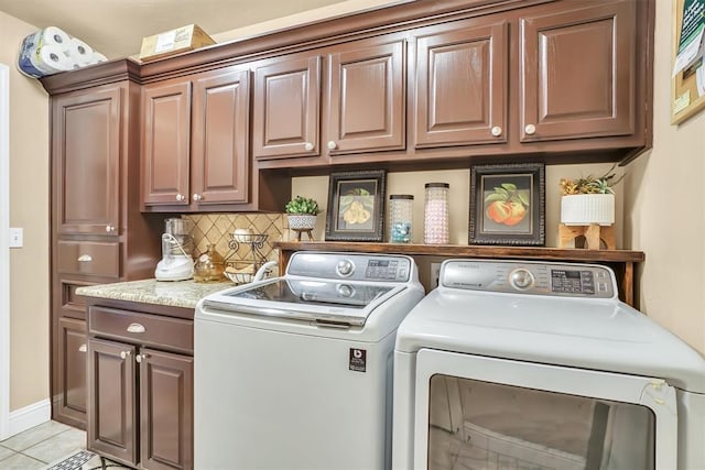 laundry area with light tile patterned floors, baseboards, washing machine and dryer, and cabinet space