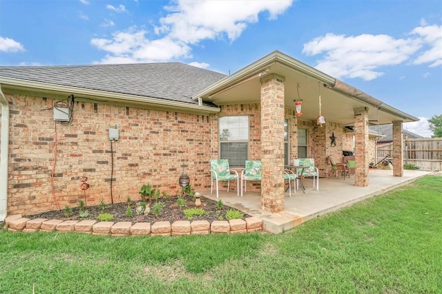 rear view of house with roof with shingles, fence, a patio, and a yard