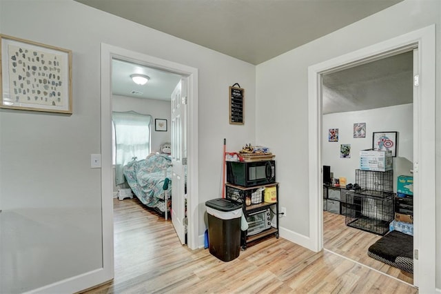corridor featuring light wood-type flooring and baseboards