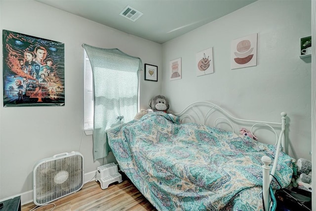bedroom with baseboards, visible vents, and wood finished floors