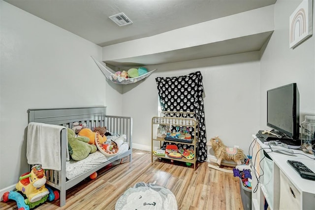 bedroom with visible vents, baseboards, and wood finished floors