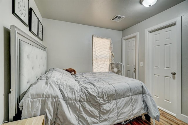bedroom featuring wood finished floors and visible vents