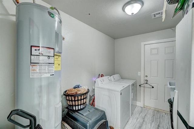 washroom with light wood-style floors, laundry area, visible vents, water heater, and washer and clothes dryer