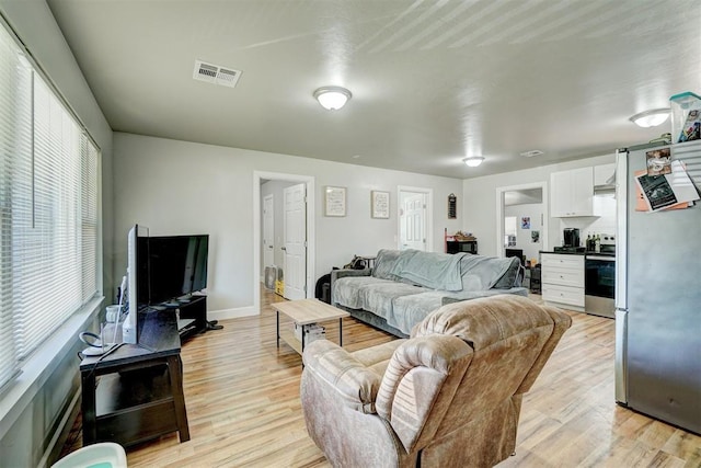 living room featuring baseboards, light wood-style flooring, and visible vents