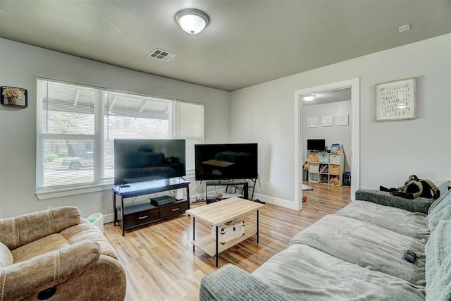 living room featuring baseboards, visible vents, and light wood-style flooring