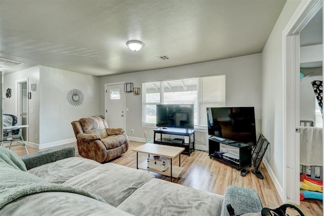 living room featuring baseboards, visible vents, and wood finished floors