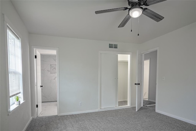 unfurnished bedroom featuring connected bathroom, ceiling fan, visible vents, baseboards, and light colored carpet