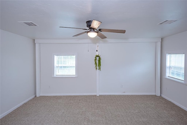 carpeted spare room featuring visible vents, a ceiling fan, and baseboards