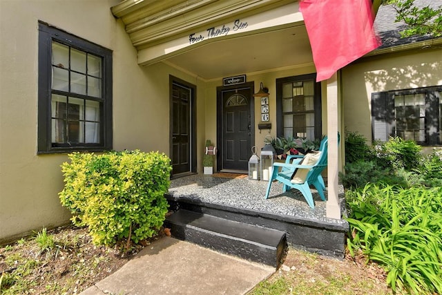 property entrance with covered porch and stucco siding