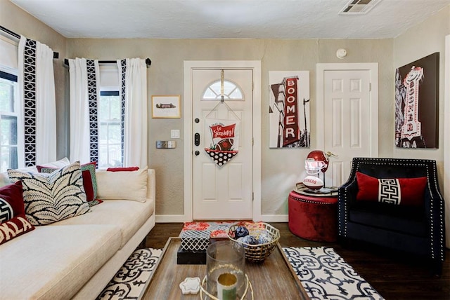 foyer entrance featuring visible vents, wood finished floors, and baseboards