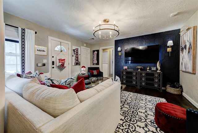 living area featuring wood finished floors, a textured ceiling, visible vents, baseboards, and a chandelier