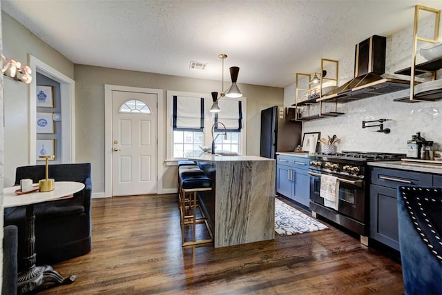 kitchen with a breakfast bar area, exhaust hood, high end stove, visible vents, and tasteful backsplash