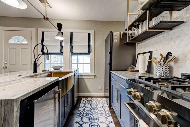 kitchen with a sink, stainless steel appliances, a textured wall, dark wood-style floors, and beverage cooler