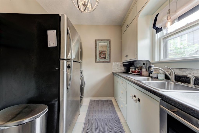kitchen featuring a sink, washer / clothes dryer, freestanding refrigerator, light tile patterned flooring, and dishwashing machine