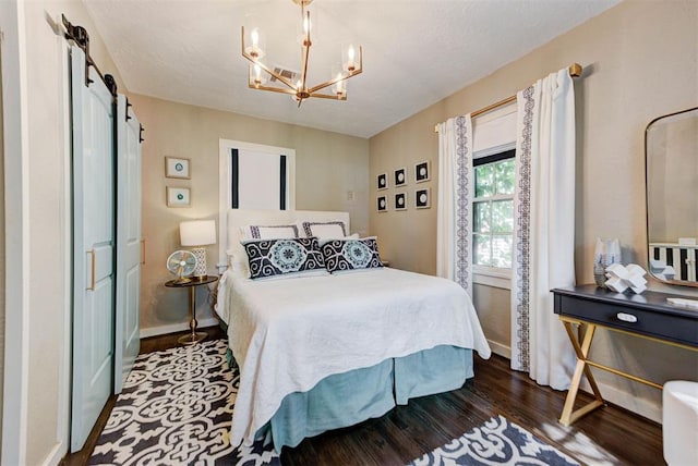bedroom with baseboards, a notable chandelier, dark wood finished floors, and a barn door