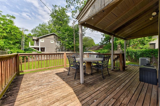 deck with a fenced backyard, outdoor dining area, central AC unit, and a lawn
