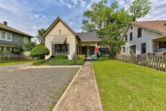 bungalow-style home featuring a front yard, stucco siding, and fence