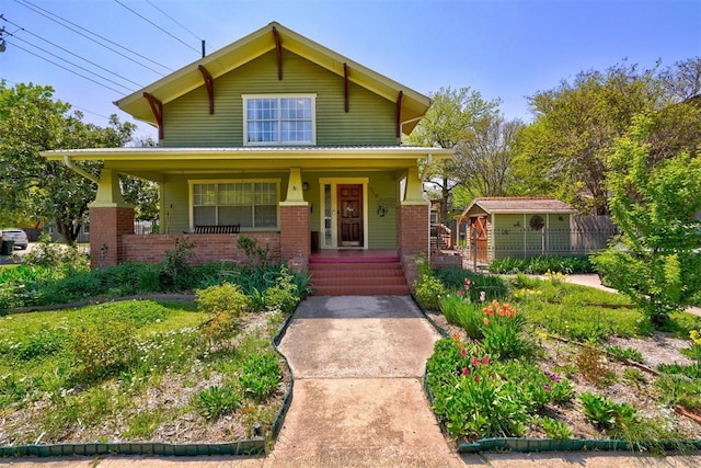 318 College Ave, Norman, OK 73069 - view of front of house featuring covered porch, brick siding, an outdoor structure, and a storage unit