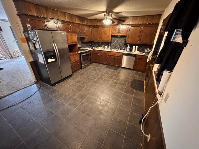 kitchen featuring ceiling fan, backsplash, appliances with stainless steel finishes, a sink, and under cabinet range hood