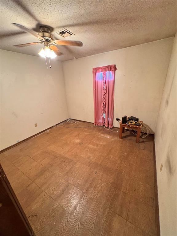 spare room with a ceiling fan, a textured ceiling, and visible vents