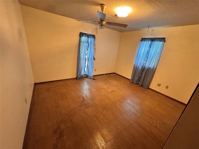 empty room with tile patterned floors, baseboards, a ceiling fan, and a textured ceiling